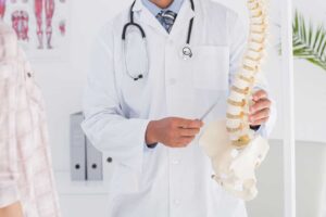 A person adjusts their ergonomic chair and computer monitor while stretching their neck at a desk.
