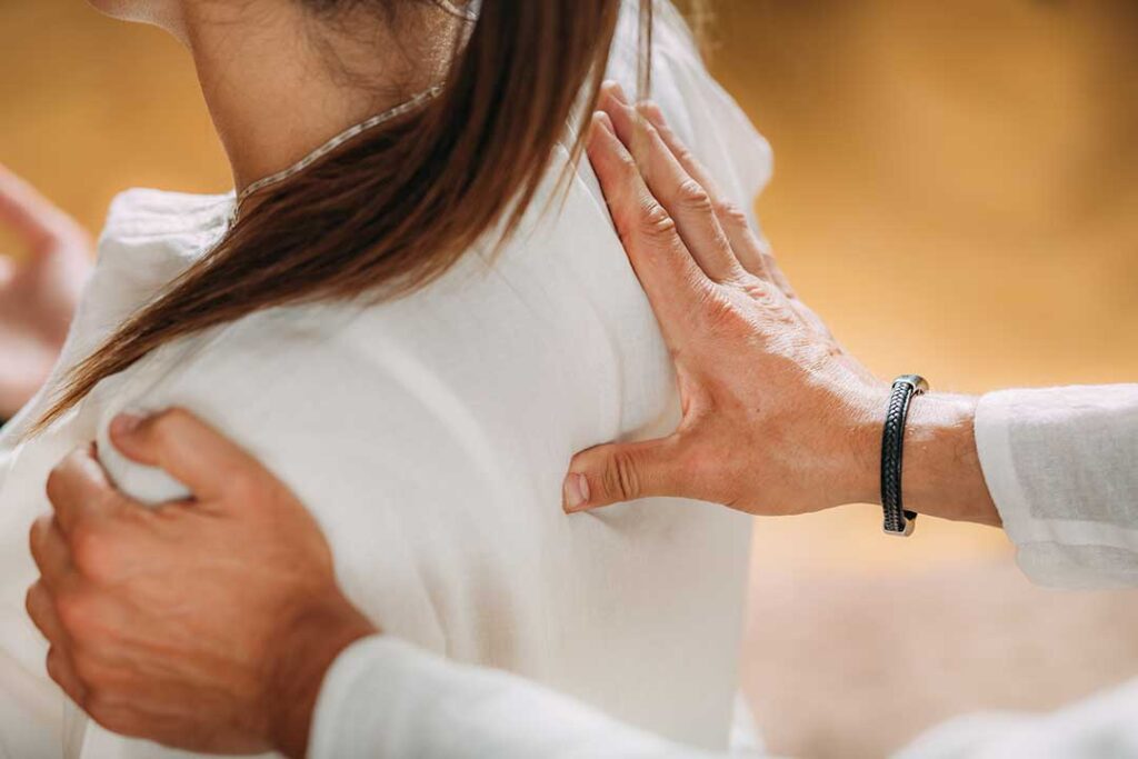 A chiropractor gently adjusts a patient's back in a comfortably lit treatment room.