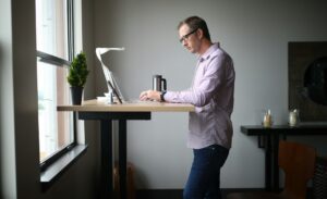Person sitting at a desk with a raised laptop, supported lower back, and relaxed shoulders during a work break