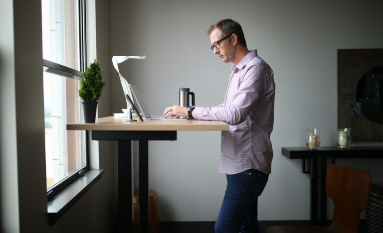 Person sitting at a desk with a raised laptop, supported lower back, and relaxed shoulders during a work break